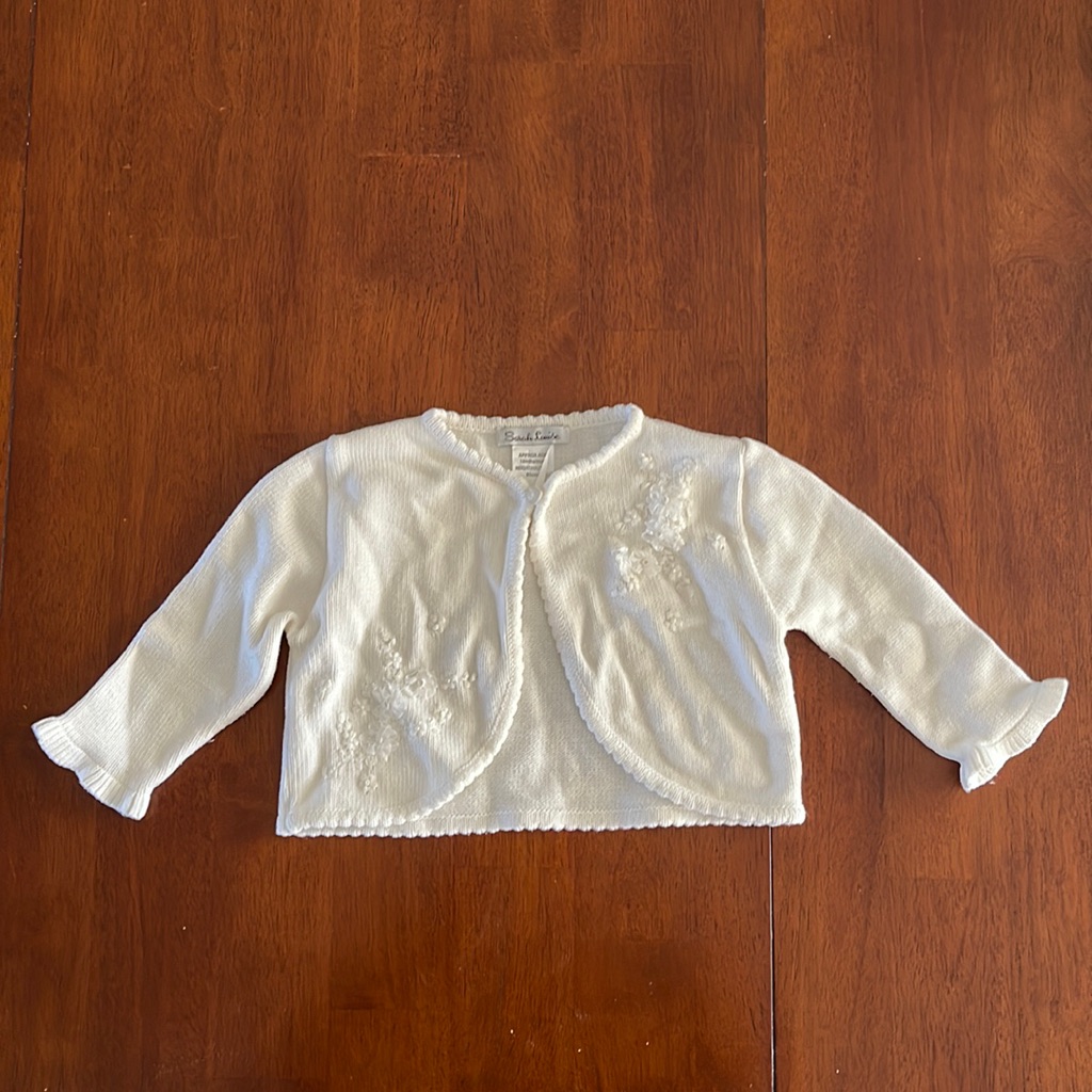 White Baby Sweater With 1 Button Closure At The Top. Also Has Flower Design.